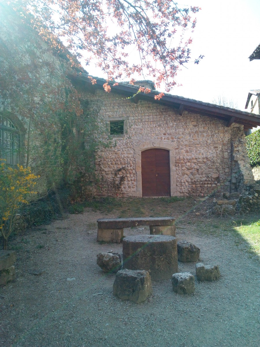 Table en pierre avec banc, devant maison en pierre blanche à Pérouges