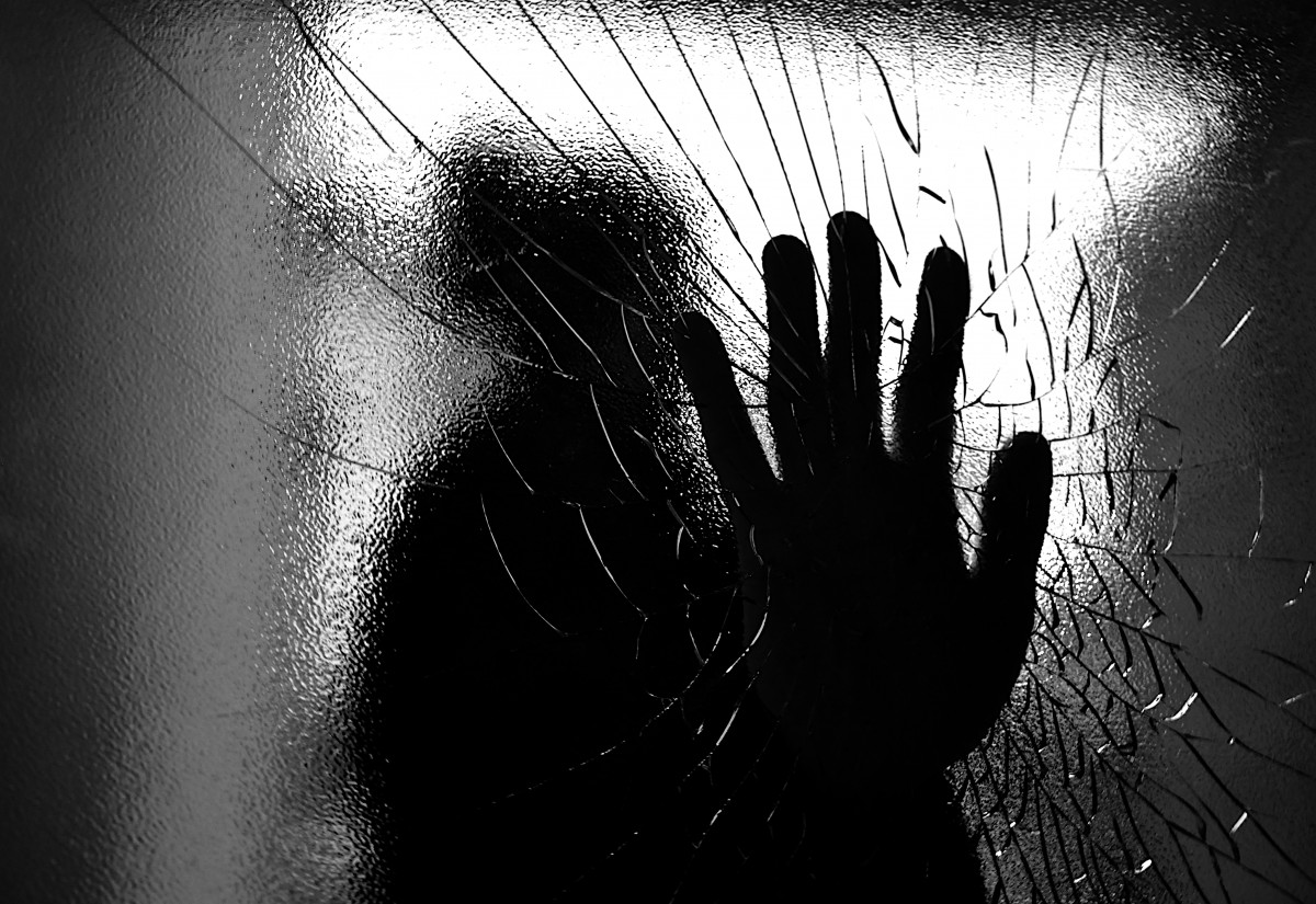 Une silhouette casse une vitre avec la main