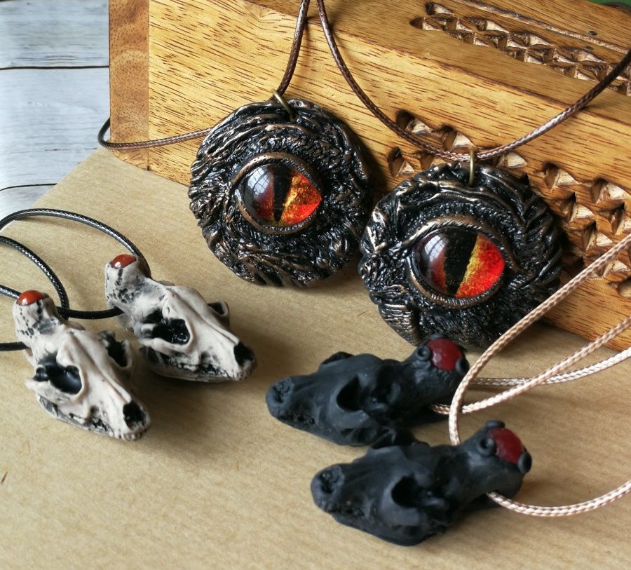 Bijoux de la Manufacture du Serpent Cosmique sur le thème Infiltrés : deux crânes de loups blancs avec pierre, deux yeux rouges, et deux crânes noirs avec pierre rouge