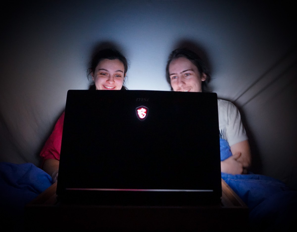 une femme et un homme, Fleur et Florian de l'équipe du Projet CarTylion, assis sur le lit en train de regarder un film sur l'ordinateur