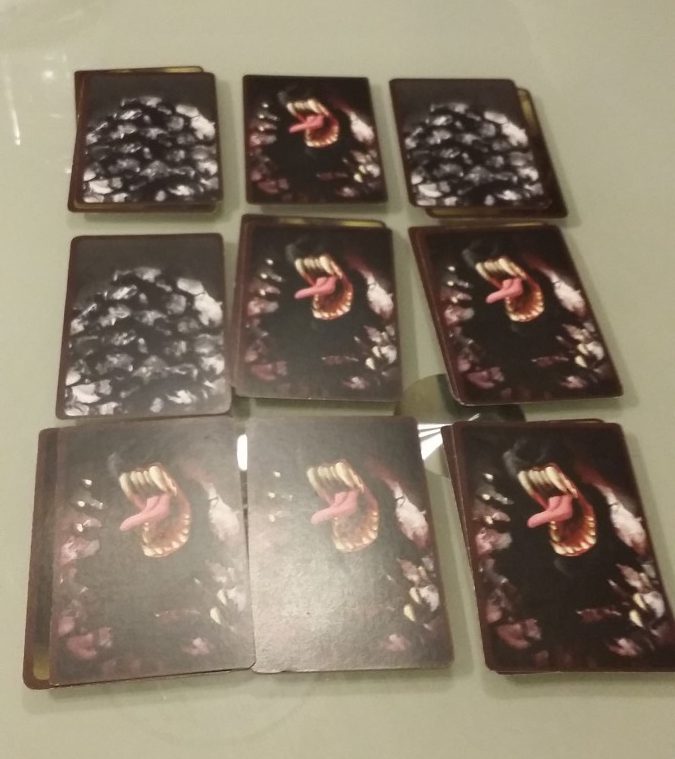 9 piles de cartes du jeu Infiltrés avec des tas de charbon et des loups-garous