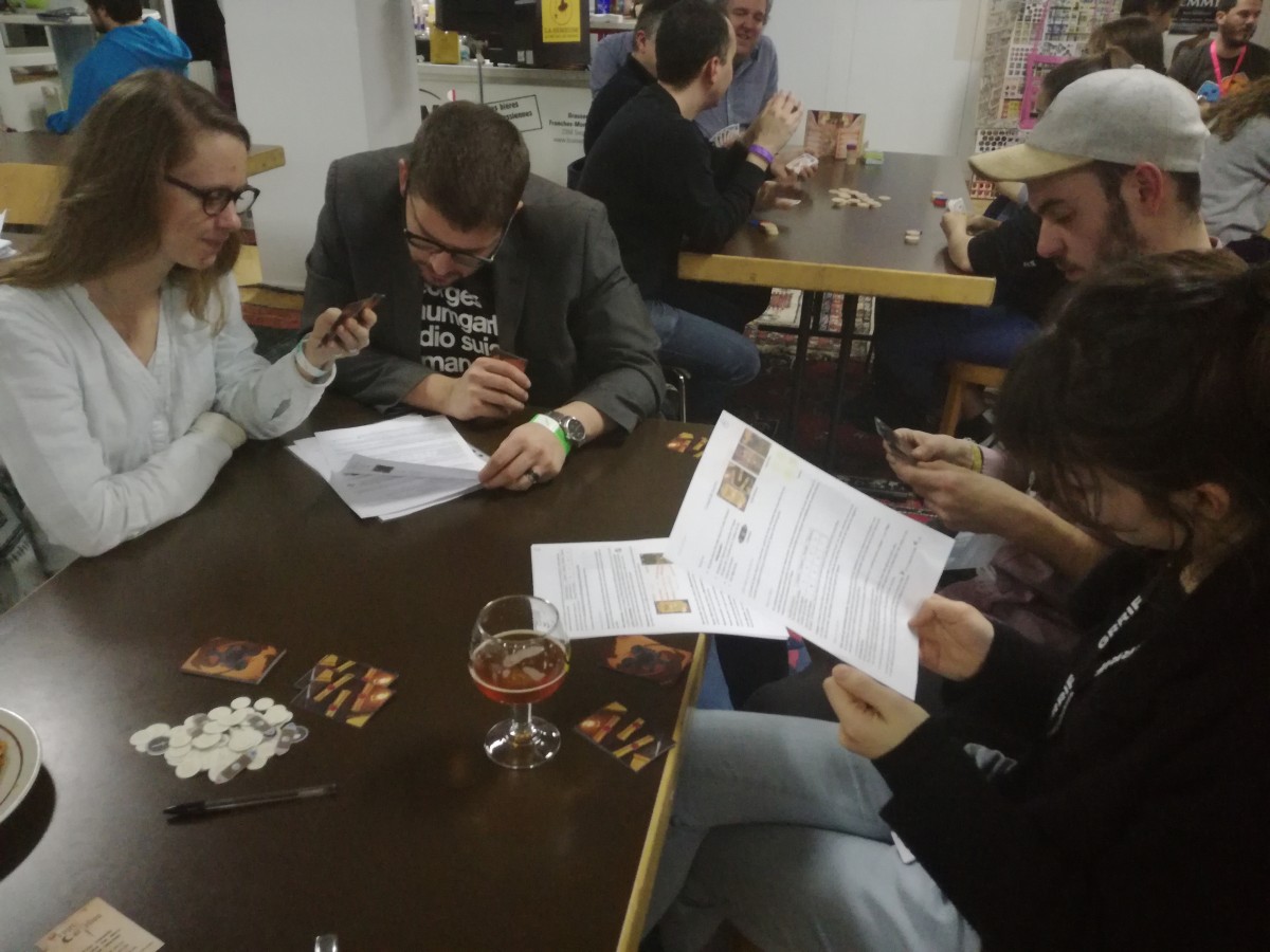 4 joueurs testant Conseil de Guerre : règles en main, cartes et jetons. Festival Ludesco 2018