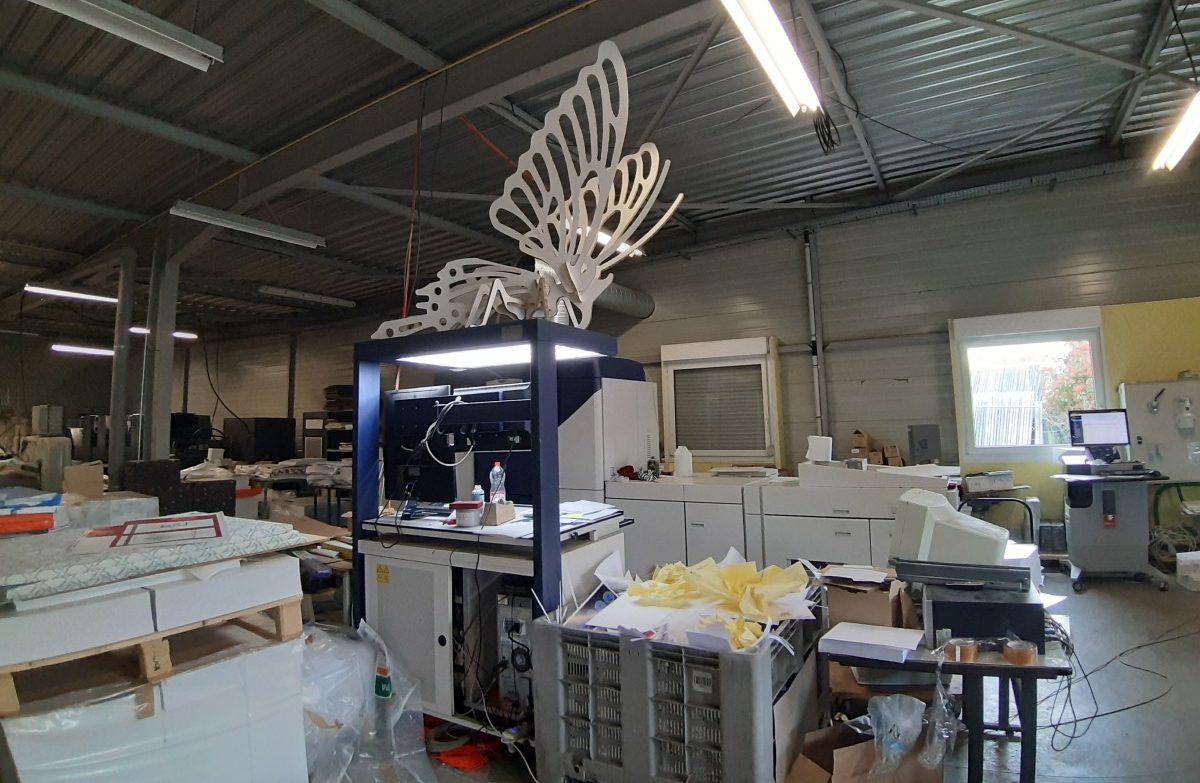 Image d'une imprimerie avec une sculpture en carton au-dessus des machines
