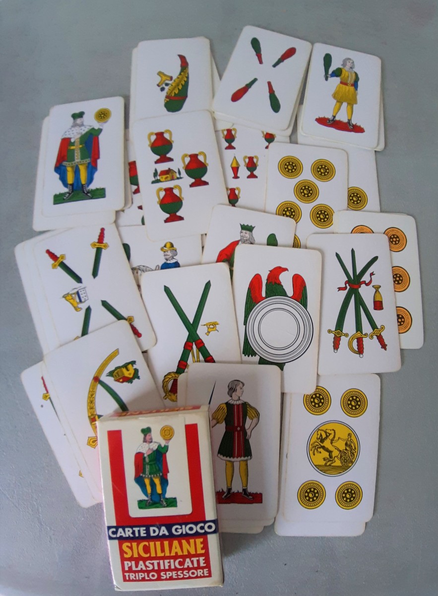 Paquet de jeu de cartes écrit en italien et plusieurs cartes montrées : baton, épée, coupe et écu