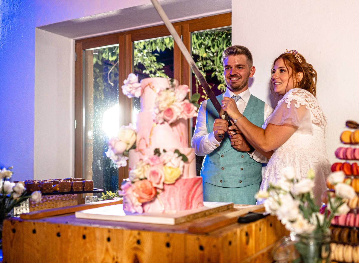Quentin et Lydie coupent le gâteau de mariage rose avec une épée