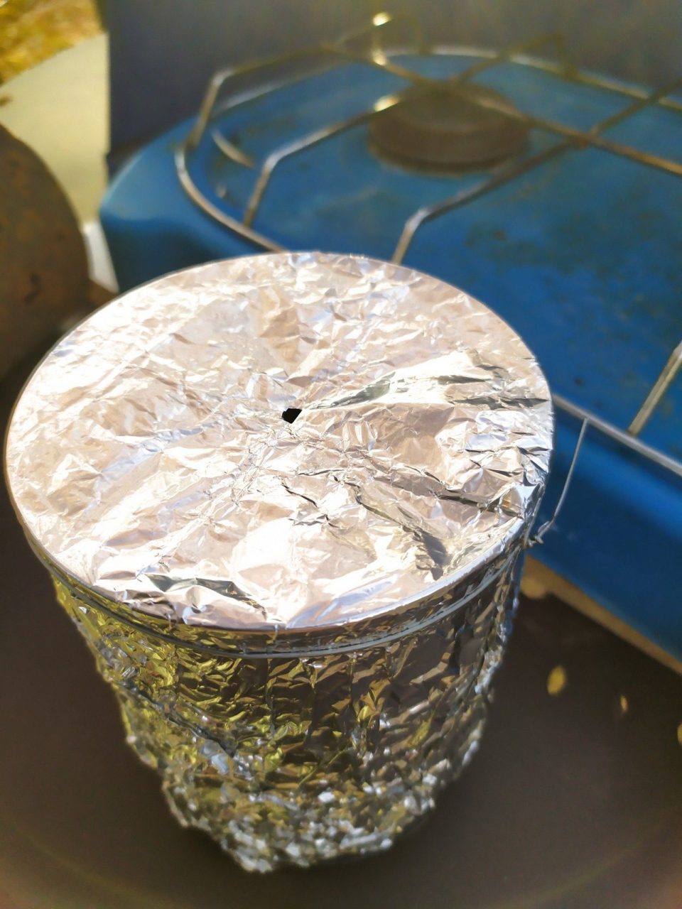 Une boîte de conserve couverte d'aluminium à côté d'un réchaud gaz d'appoint