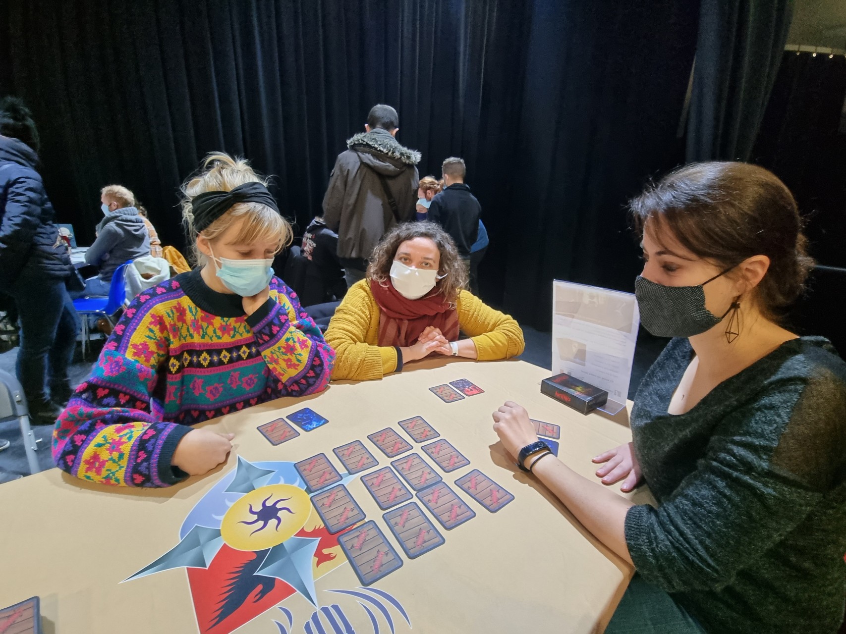 3 joueuses testent la variante Raid du jeu Infiltrés sur une table du Projet CarTylion à la MJC Le Sillon Chemin-Vert à Caen lors du Festival du jeu et de l’imaginaire