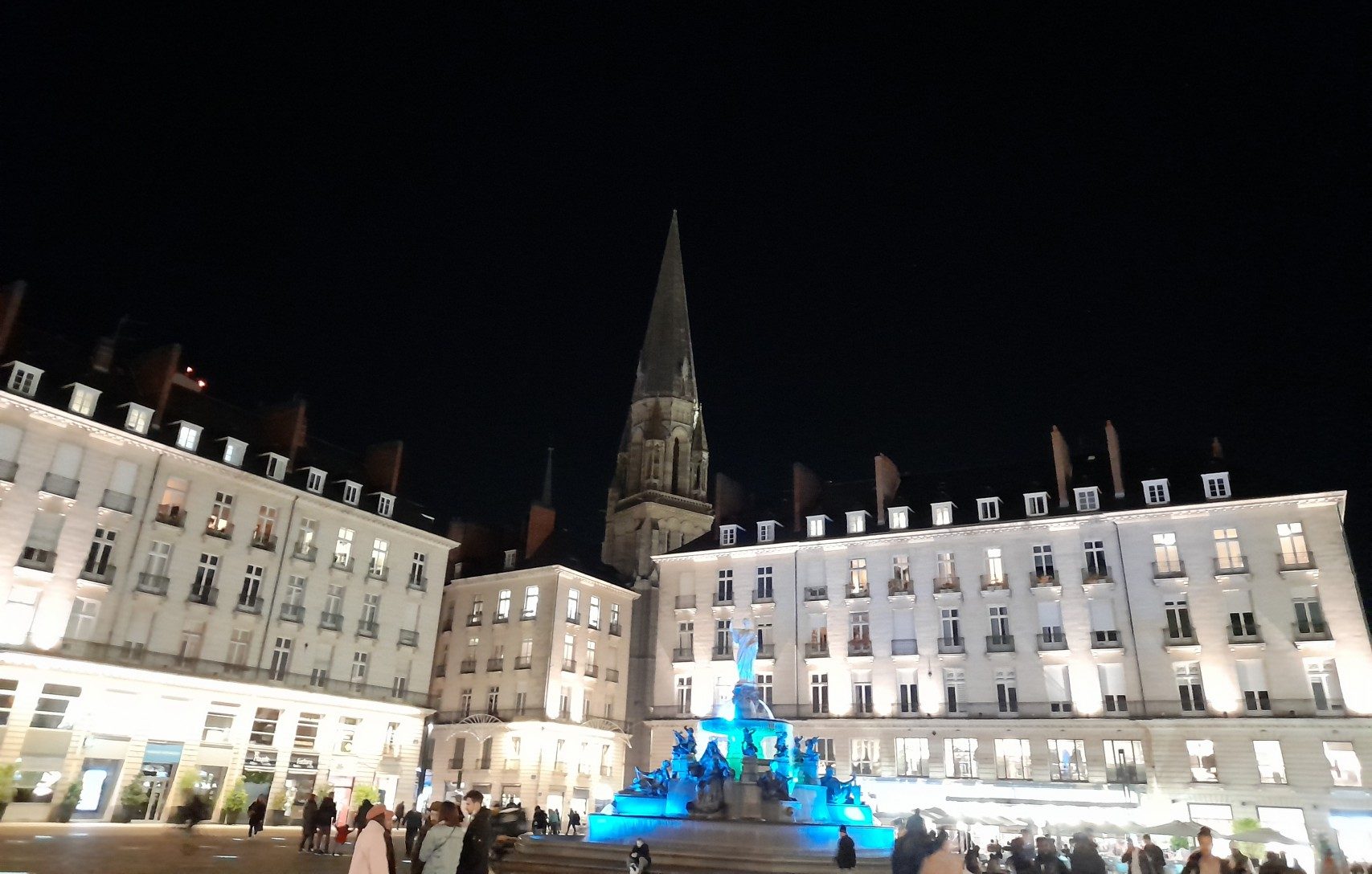 Angle de la Place Royale de Nantes de nuit une fontaine illuminée en bleu devant des immeubles