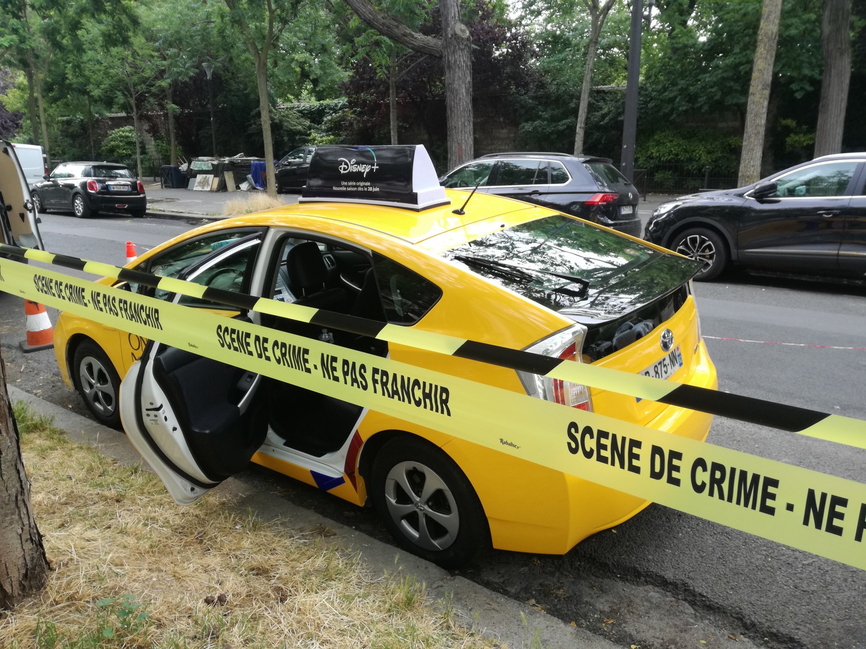 Taxi jaune aux couleurs de Disney + et bandeau "Scène de crime - Ne pas franchir"