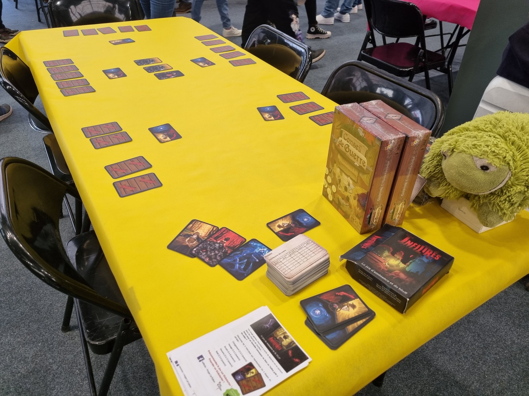 Table avec une nappe jaune et les jeux Infiltrés et Conseil de Guerre