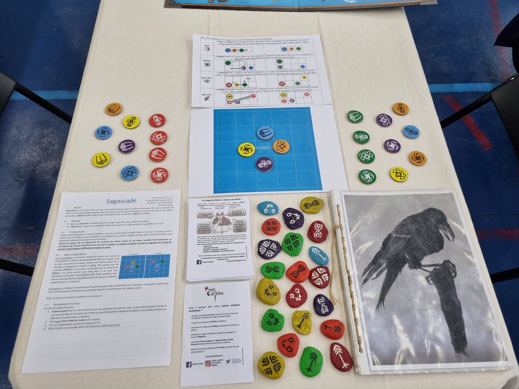 Table de jeu avec le jeu Sagascade présenté et des flyers du Projet CarTylion