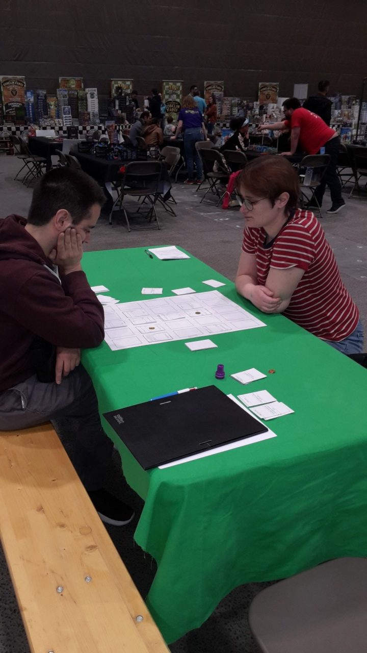 Deux joueurs devant une table à la nappe verte en train de joueur à la Bataille éternelle à Ludiquest